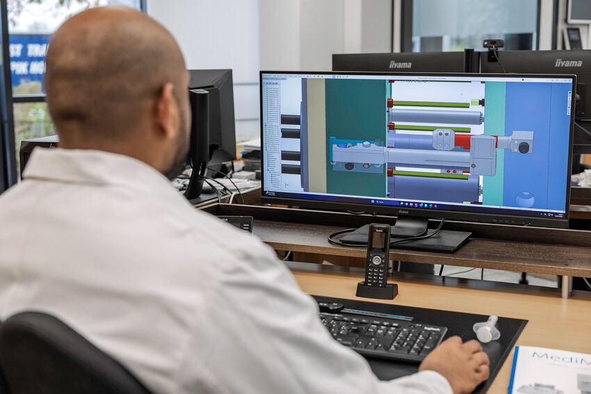 Ein MFORM-Mitarbeiter sitzt vor einem Bildschirm, auf dem eine 3D-Zeichnung zu sehen ist