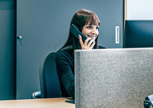 Eine MFORM-Mitarbeiterin telefoniert lächelnd